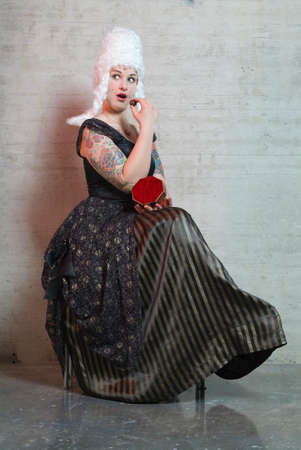 a young woman with a white peruke eats a chocolate