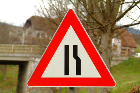 a traffic sign for the road constriction with backgroundの写真素材