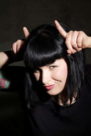 a woman with black hair and piercing shows hornsの写真素材