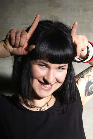 a woman with black hair and piercing shows hornsの写真素材