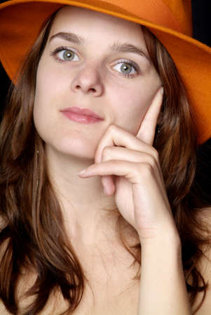 young woman with orange hat hold face