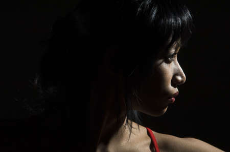 edgewise portrait of young woman black backgroundの写真素材