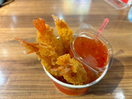 Fried shrimp with sweet and sour sauce in a plastic cup.
