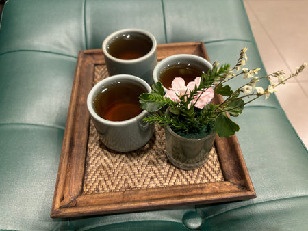 Three cups of green tea on a wooden tray with a bouquet of flowersの写真素材