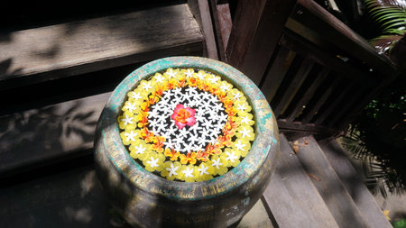 Thai style clay pot with flower on wooden stairs in the gardenの写真素材