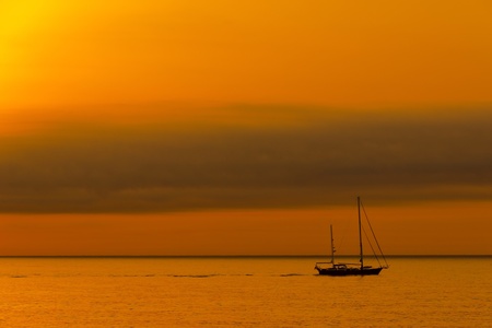 Dawn sailboat silhouette on oceanの写真素材