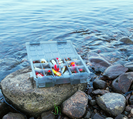 Colorful fishing fish lures in a box in coast river