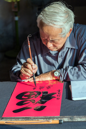 Hanoi, Vietnam - November 20, 2014 Calligrapher writing words on paper. Calligraphy is old culture of Vietnamのeditorial素材