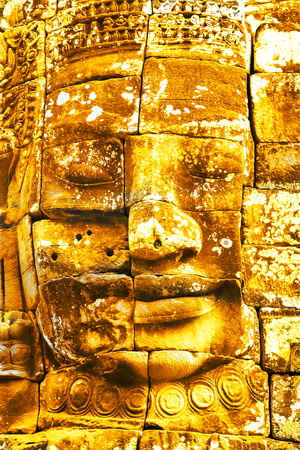 Gold Stone head in ancient Bayon Temple Angkor Thom, Cambodia. Ancient monument Khmer architecture.の写真素材