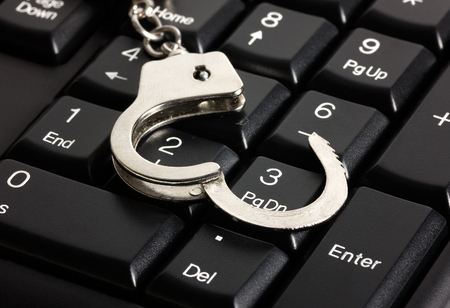 computer keyboard and handcuffs, crime computers technology isolated on white background.の写真素材