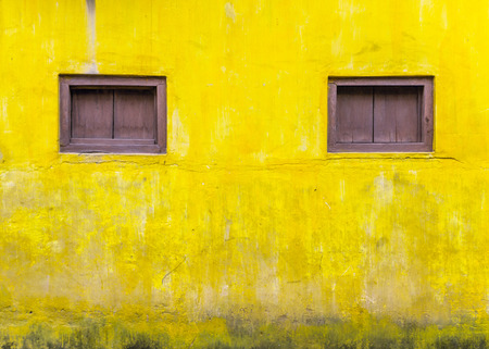 Yellow cement wall with Dark brown windows old frameの写真素材