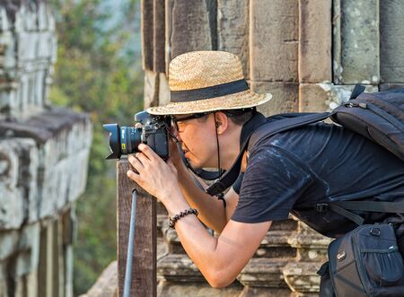 SIEM REAP, CAMBODIA - March 01, 2015: Traveler photographer asian man in hat Angkor Wat is a popular tourist attraction temple in Angkor Archeological area in Cambodiaのeditorial素材