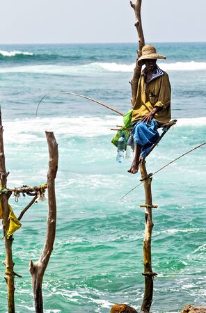 KOGGALA, Sri Lanka - February 09, 2016: Local fisherman on stick on a beach of Indian ocean, Sri Lanka.のeditorial素材