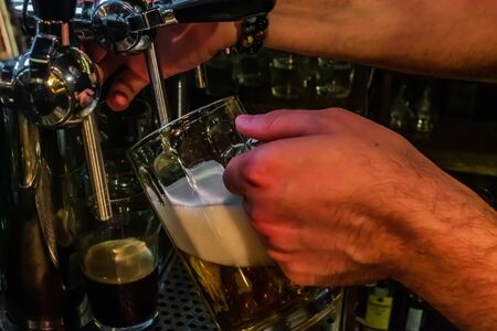 Barmen filling plastic glass with light beer Bar or night club