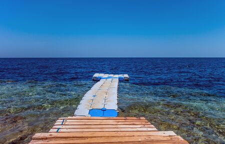 Floating swimming pier pontoon with clean water red sea beach landscape scene background.