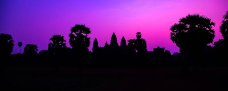 Panorama Mist sunrise tropical morning violet mauve sky landscape. Palm trees Famous facade silhouette of Cambodian ancient temple Angkor wat, Angkor Archaeological Park near Siem Reap in Cambodia.の写真素材