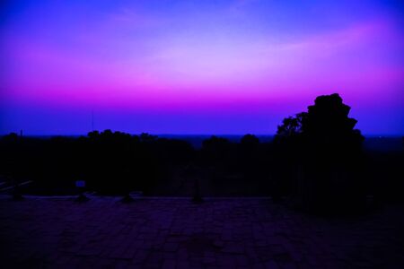 Panorama Mist sunrise tropical morning violet mauve colorful sky landscape. Palm trees silhouette of Cambodian ancient temple Angkor wat, Siem Reap in Cambodia.の写真素材