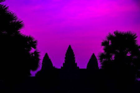 Silhouette of Cambodian ancient temple Angkor wat, Angkor Archaeological Park near Siem Reap in Cambodia. Panorama Mist sunrise tropical morning violet mauve colorful sky landscape Palm trees.の写真素材