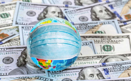 Quarantine emergency lockdown world. Mask Medical virus protection on globe map continents travel background one hundred dollar banknote. Economy crisis Concept covid-19.の写真素材