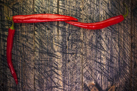 Art background with red peppers on wooden boardの写真素材