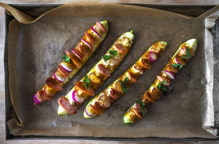 Stuffed grilled zucchini with radishes and sausage on a baking sheetの写真素材