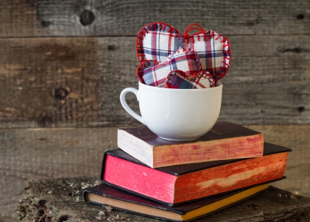 Three hearts in a white mug on books on a wooden boardの写真素材