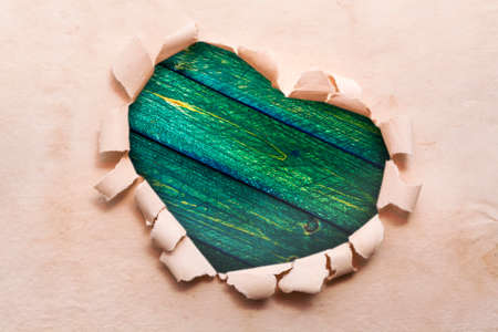 Heart ripped out in the paper and in the middle of deskの写真素材