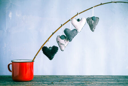 Heart hanging on a twig in a red cup