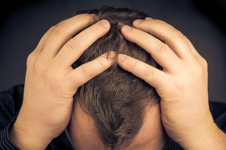 A depressed man with his hands over his faceの写真素材