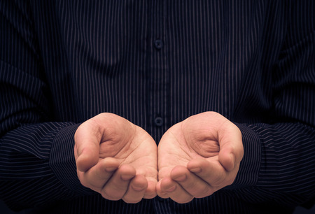 The man's hands in a gesture of holding something or ask for help