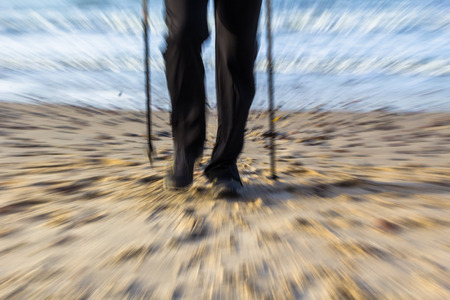Feet of man cultivating Nordic walking on the beachの写真素材