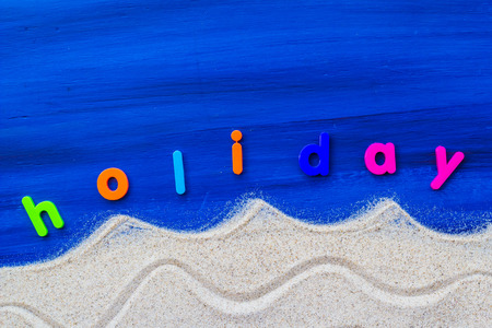 The word holiday laid sand and blue boardの写真素材