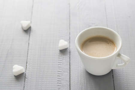 Coffee cup with milk and sugar cubes scatteredの写真素材