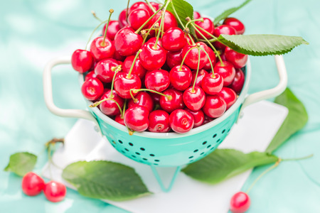 Fresh red cherry fruit in green colander