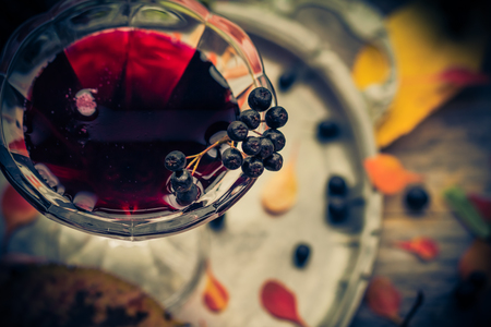 A glass of tincture of chokeberry in autumn vintage stylingの写真素材