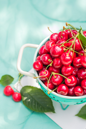 Fresh red cherry fruit in green colanderの写真素材