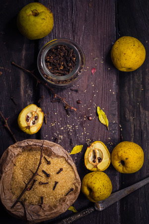 Fruits, twigs quince, sugar, cloves, vanilla on a wooden tableの写真素材