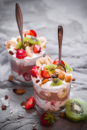 Nutrition yoghurt fruit dessert with strawberries, banana, kiwi, raisins, sunflower seeds, oatmeal and walnuts in caramelの写真素材