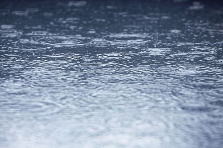 rain drops in a puddle creating ripplesの写真素材