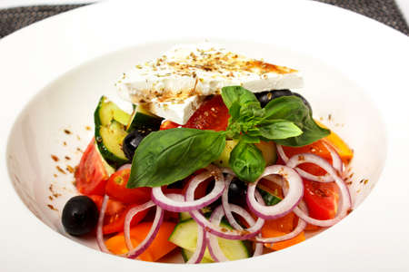 fresh greek salad in clay bowl, isolated on whiteの写真素材