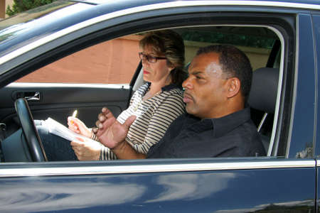 a mature African - American man having a driving test and being stressed out by the testerの写真素材