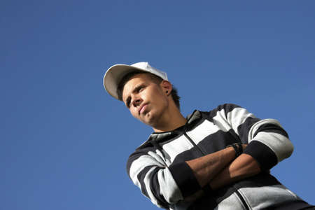 a serious looking 17-years old teenager with a baseball cap, photographed in the summer sun with...