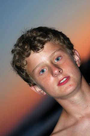 a portrait of a handsome 13-years old teenager, photographed with flashlight during sundown with the...