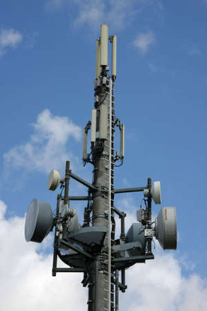 a cellular phone network mast with different kind of antennas photographed in the summer sun with...