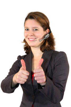 a smiling beautiful female call center agent with a headset posing with the thumbs up sign, isolated on white backgroundの写真素材