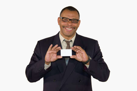 a smiling mature African-American businessman showing a business card with copy space, isolated on white backgroundの写真素材