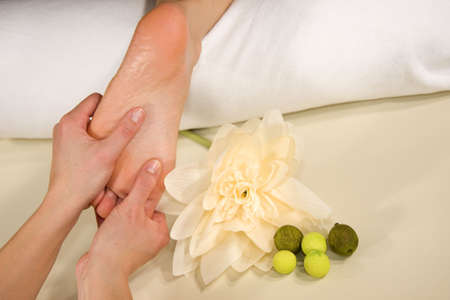 a wellness composition showing a foot of a natural mature woman having a foot reflex zone massage and a flowerの写真素材