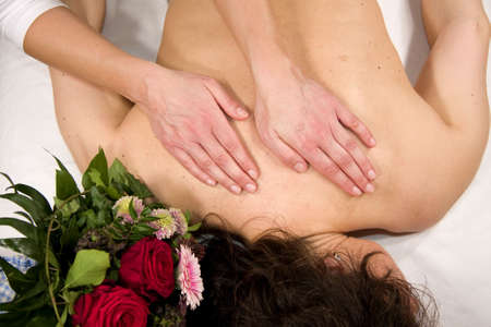 a wellness composition showing a woman having a massage at her back and a bunch of flowers lying next to her headの写真素材