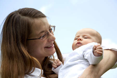A happy, smiling and proud young mother holding her 7 weeks old daughterの写真素材