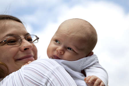 A happy, smiling and proud young mother with her 7 weeks old daughter who discovers the world around herの写真素材